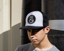 Load image into Gallery viewer, man wearing - suavecito hat with white embroidered text and black background with suavecito &quot;S&quot;
