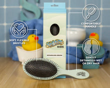 Suavecito Kids detangling brush with packaging and features on a wooden surface.