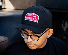 Load image into Gallery viewer, person wearing - suavecito hat with embroidered text and red background &quot;suavecito grooming m.f.g.&quot;
